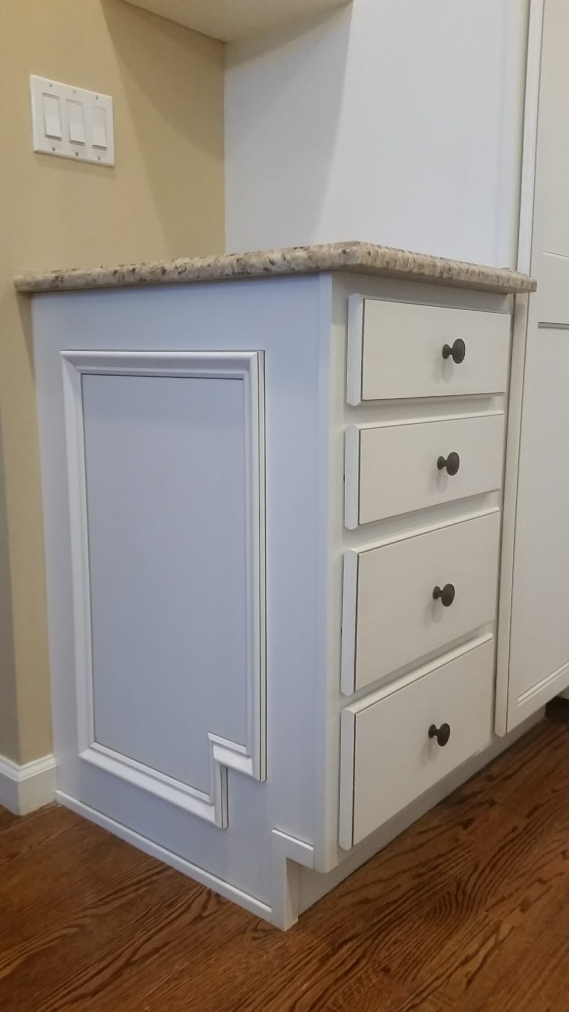 Cabinetry end panel with decorative trim and drawer fronts in off-white finish.