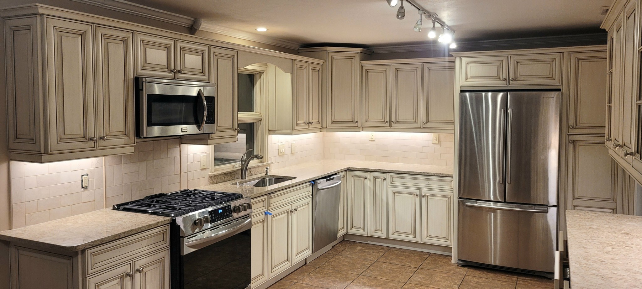 Kitchen cabinets and crown molding with off-white finish and antiquing glaze.