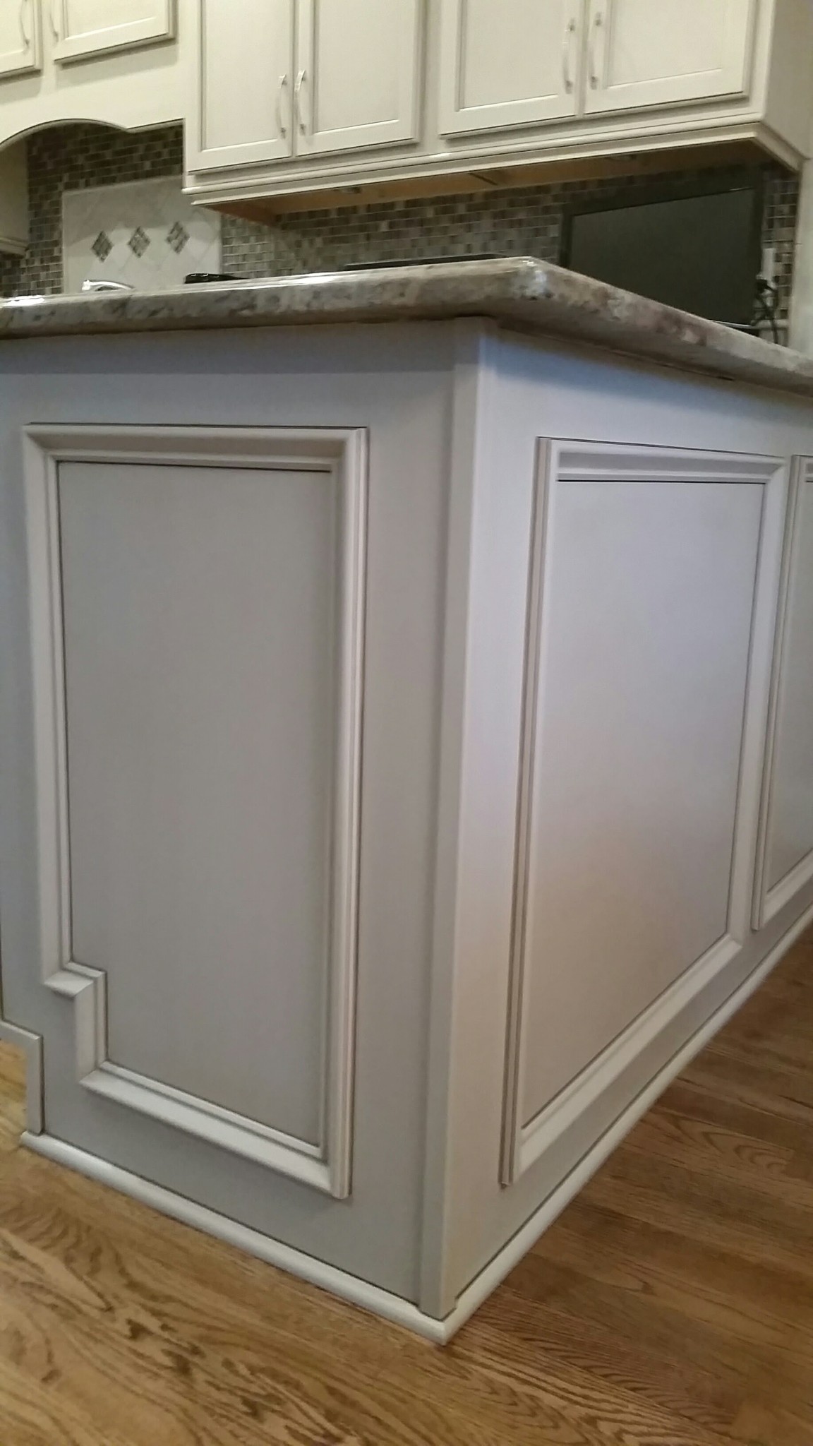 Kitchen island cabinetry refinished in light gray with antiqued trim details.