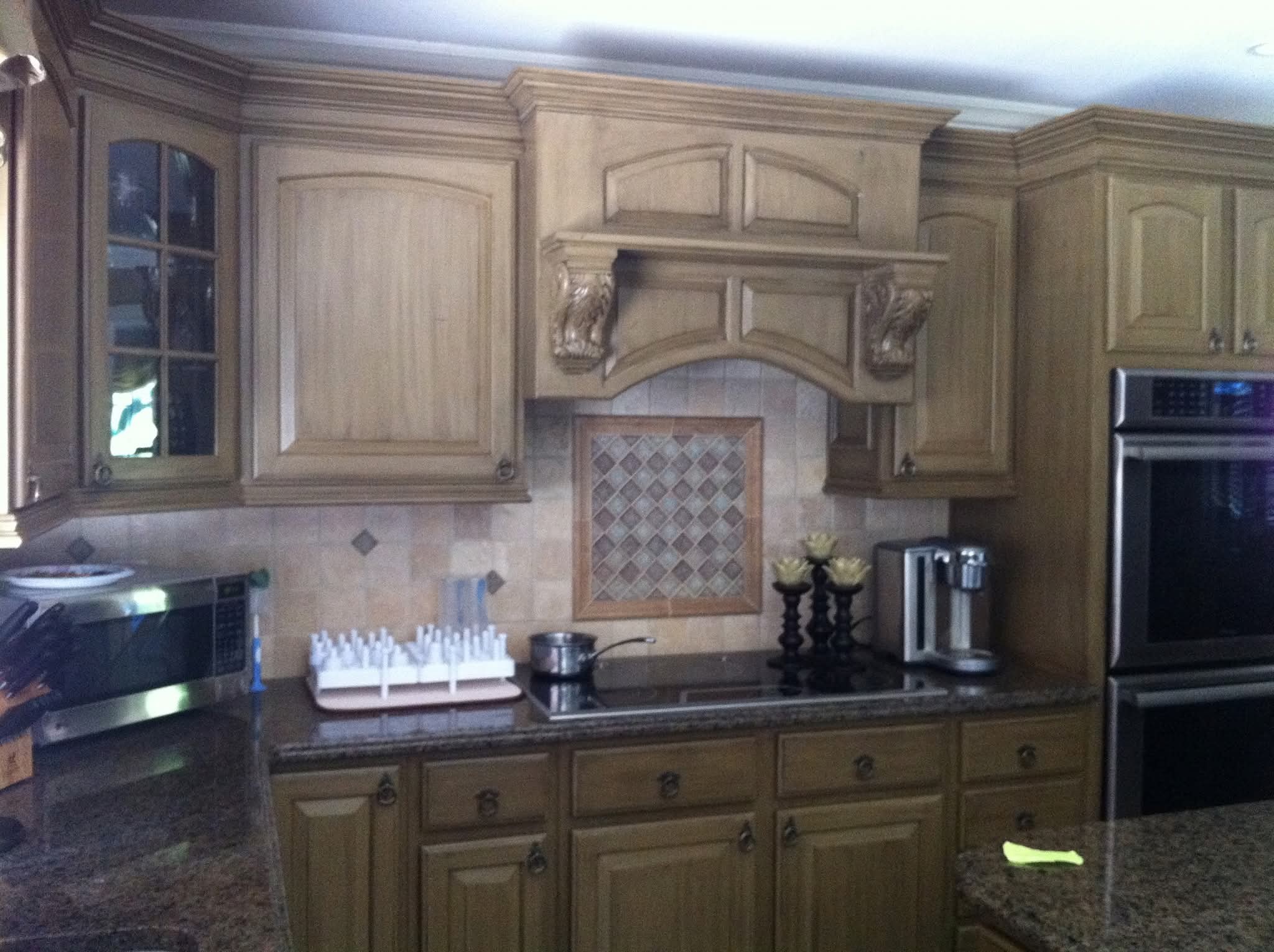 Kitchen upper and lower cabinets with distressed wood finish and decorative corbels.