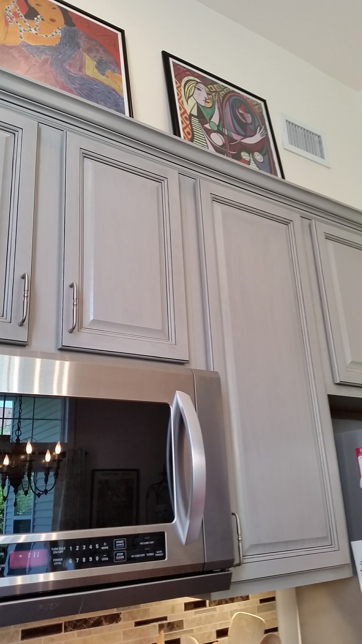 Kitchen upper cabinets and crown molding painted light gray with dark antiquing glaze.