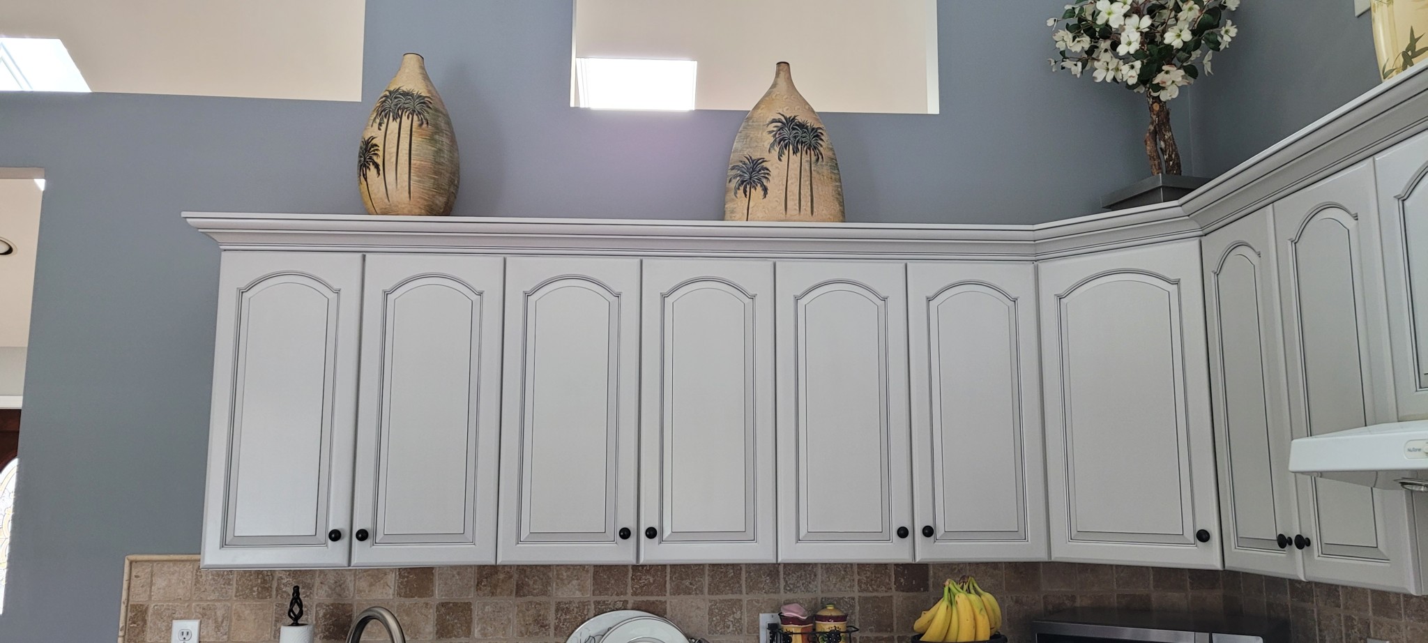Kitchen upper cabinets and crown molding refinished with off-white paint and antiquing glaze.