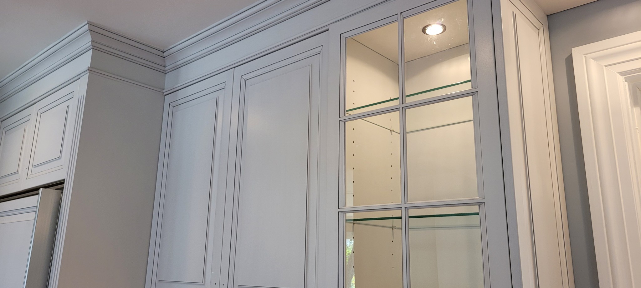 Kitchen upper cabinets, crown molding, and glass door cabinets painted light gray.