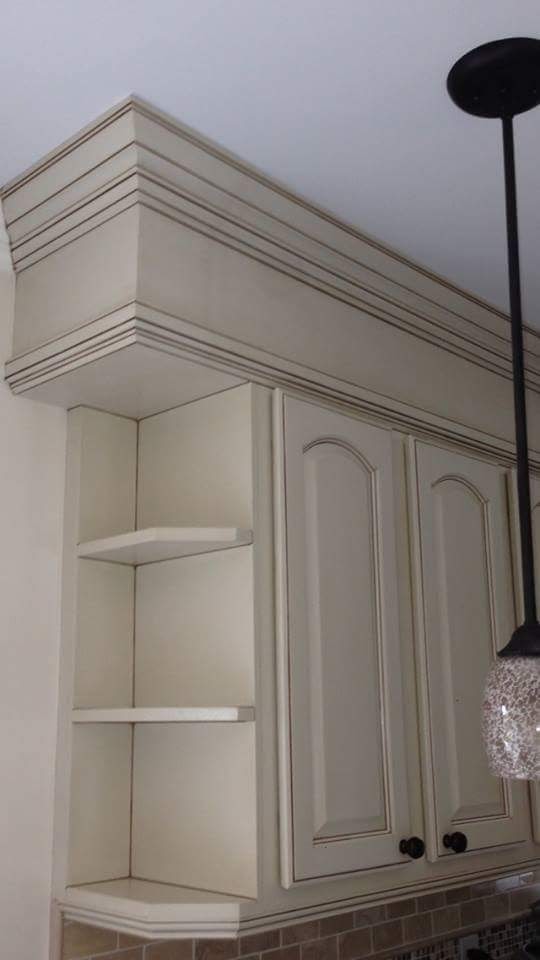 Kitchen upper cabinets, crown molding, and open shelves with antiqued finish.