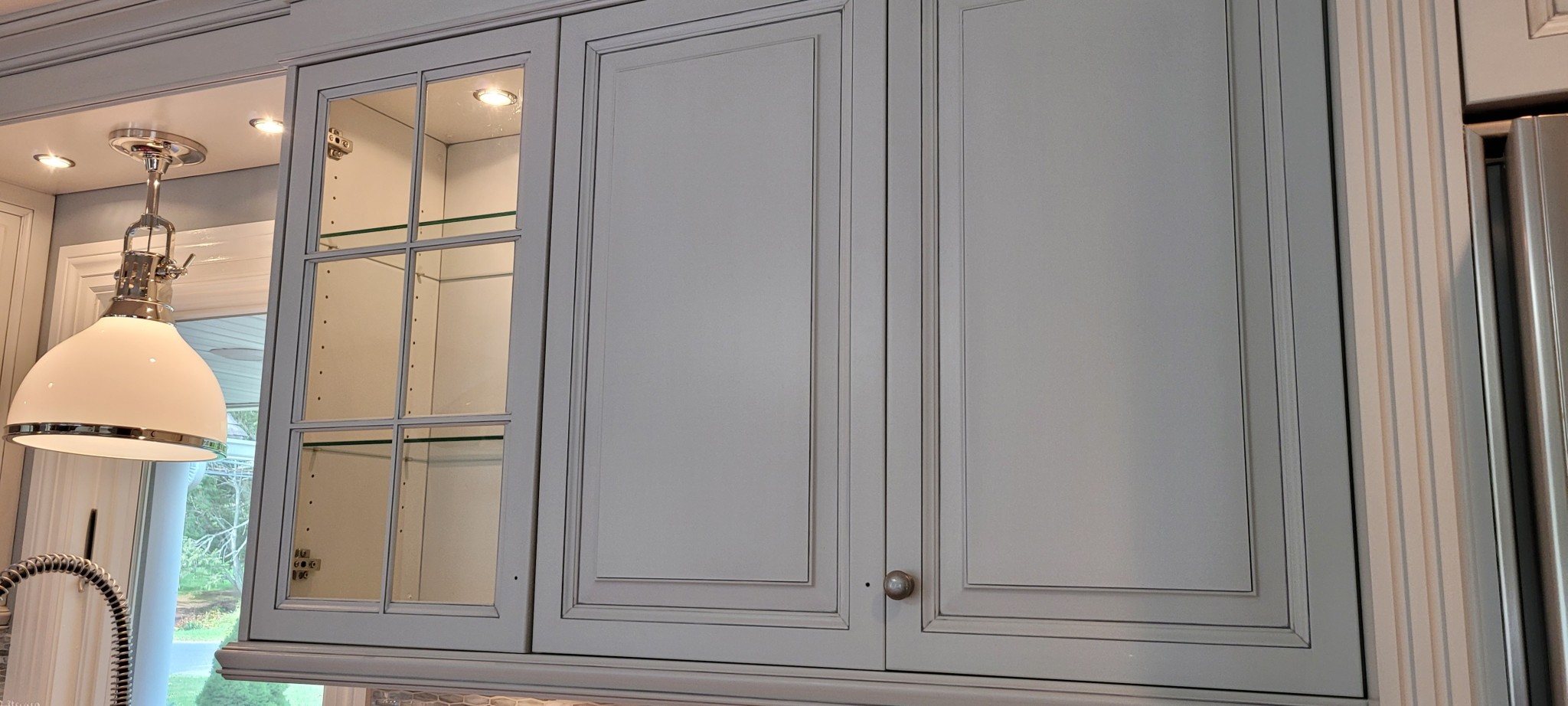 Kitchen upper cabinets with light gray painted finish and antiquing glaze visible.