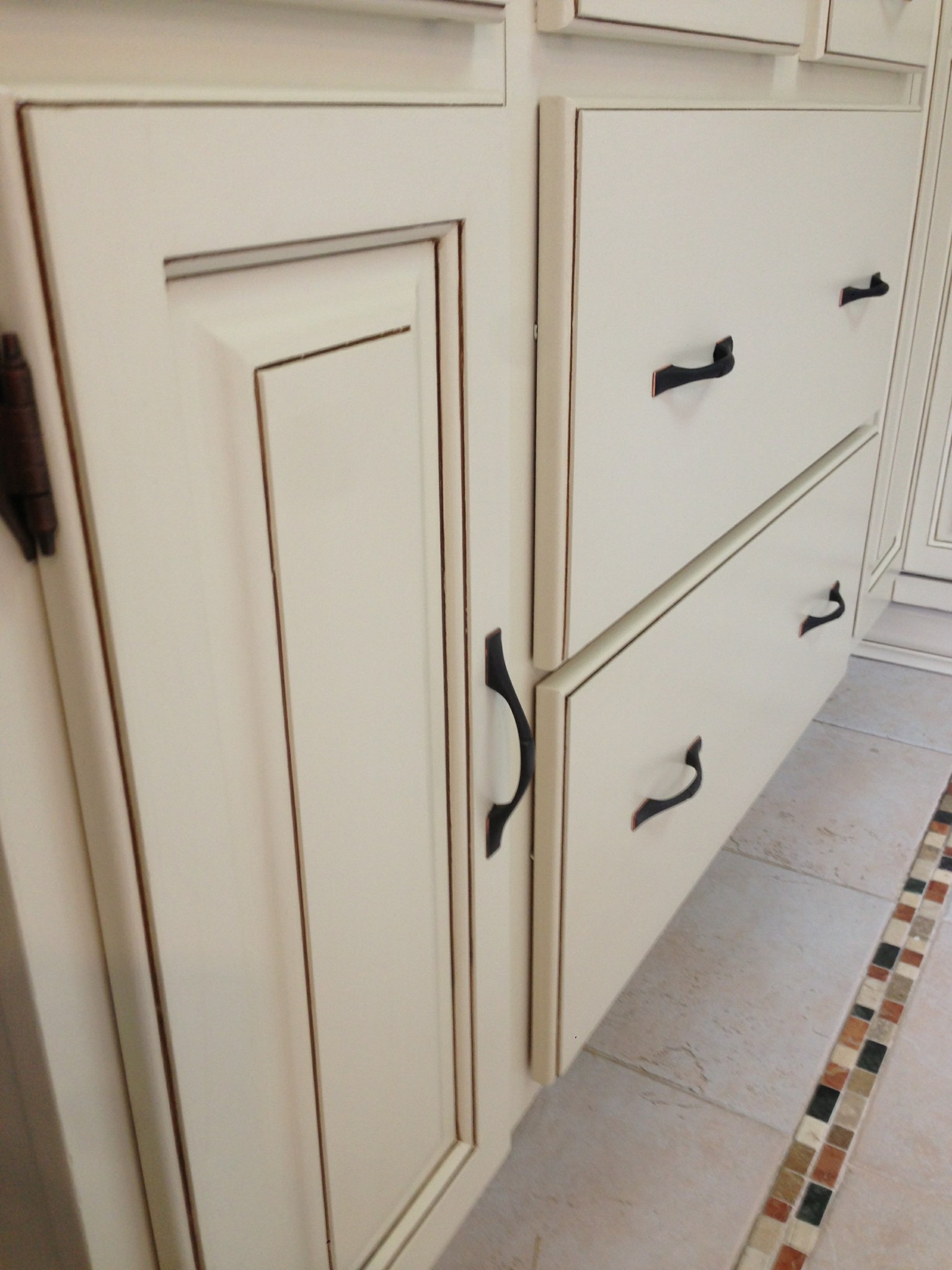 Off-white cabinet doors and drawers with antiquing technique and painted finish.