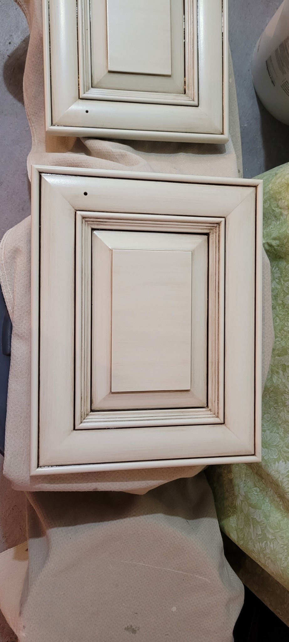 Off-white cabinet doors with antiquing technique and drilled holes for hardware.