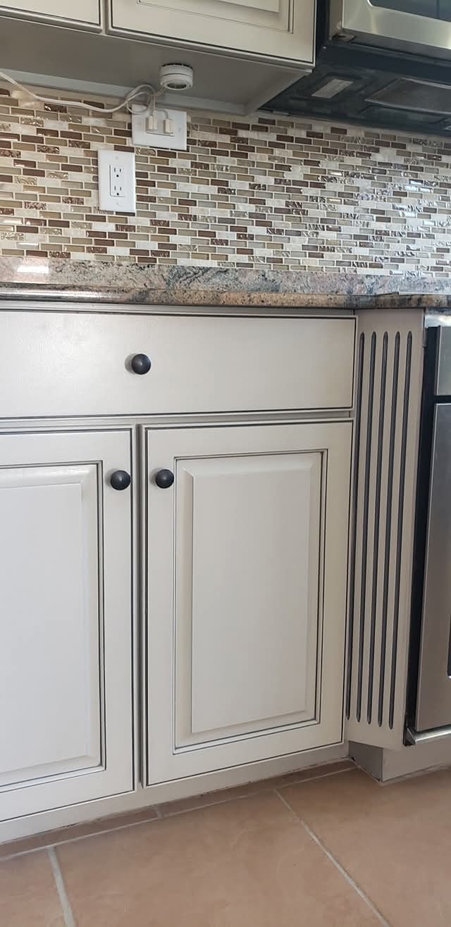 Off-white kitchen cabinet doors and drawer with antiquing finish.