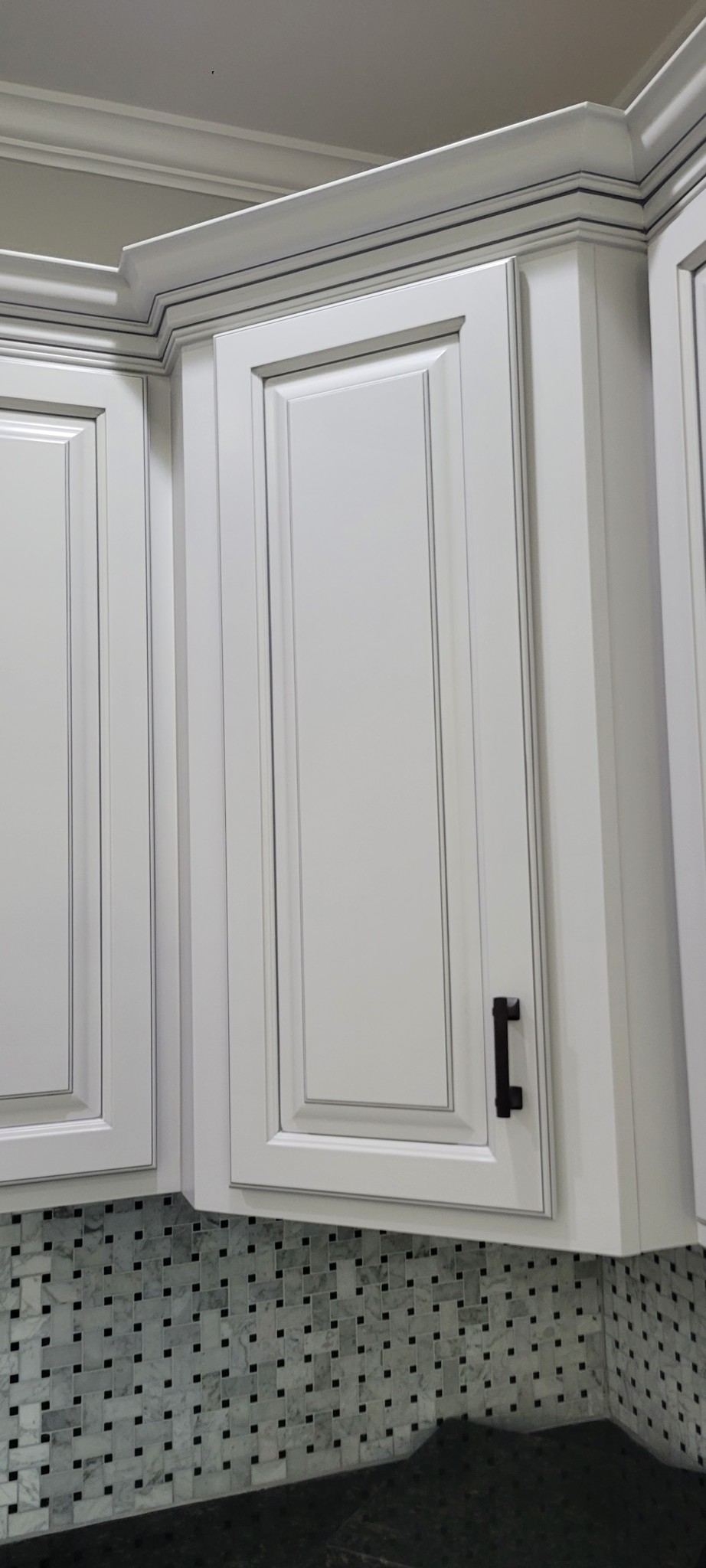 Off-white kitchen cabinet doors with applied glazing and painted crown molding.