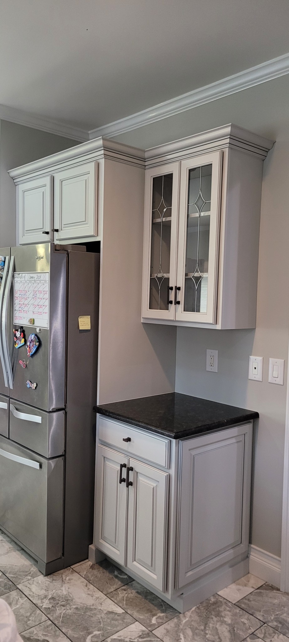 White and light gray painted kitchen cabinets with crown molding.