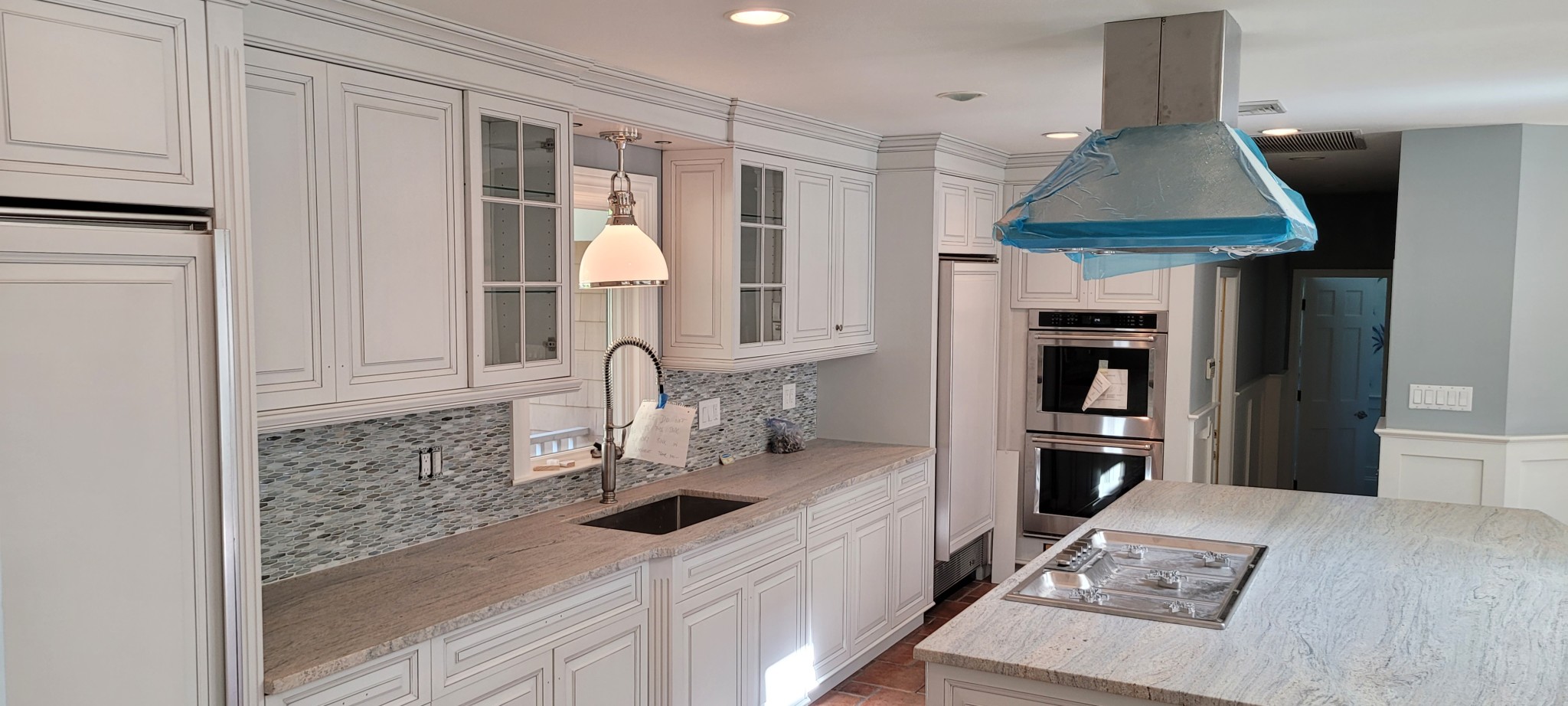 White painted kitchen cabinets, crown molding, and wainscoting with light gray walls.