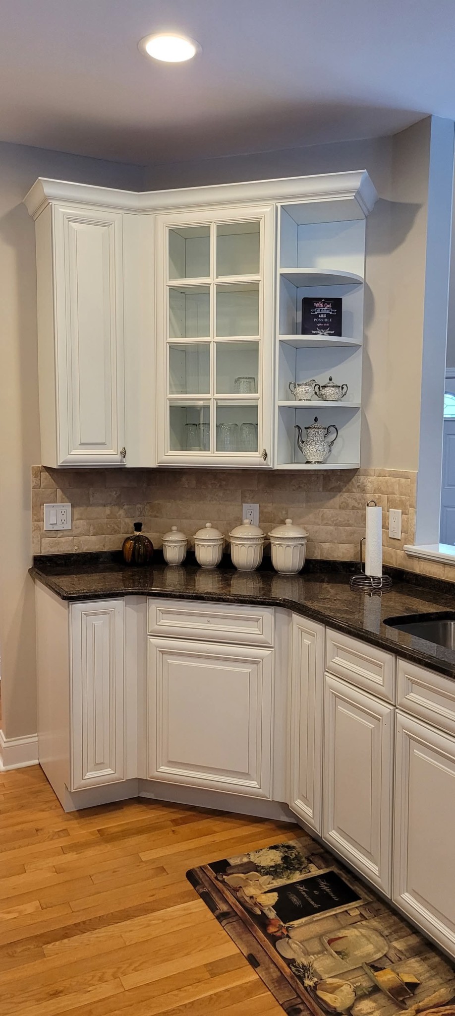 White painted kitchen cabinets, upper and lower, with crown molding and wall.