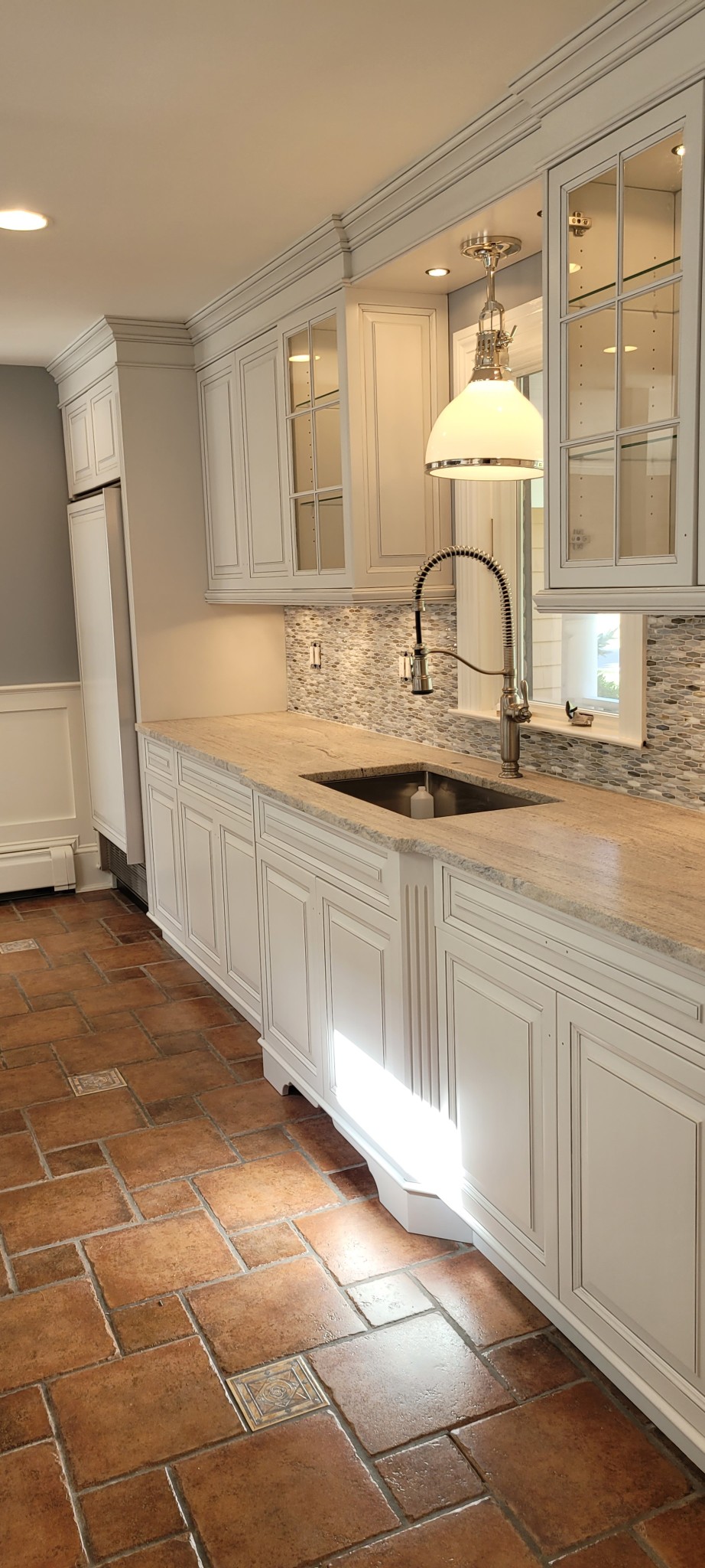 White painted kitchen cabinets with crown molding and wainscoting.