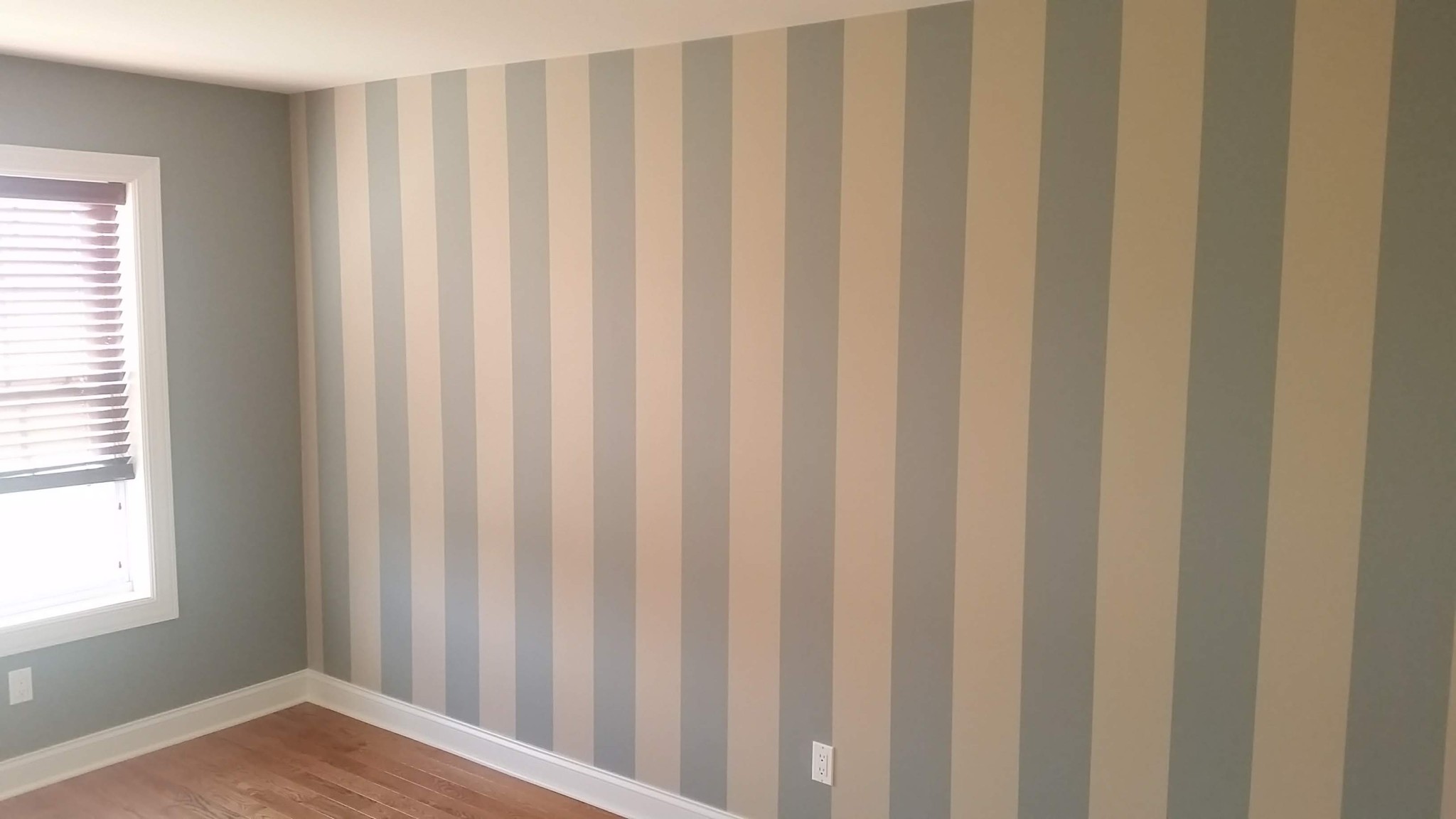 Accent wall with vertical stripes and painted trim in a room.