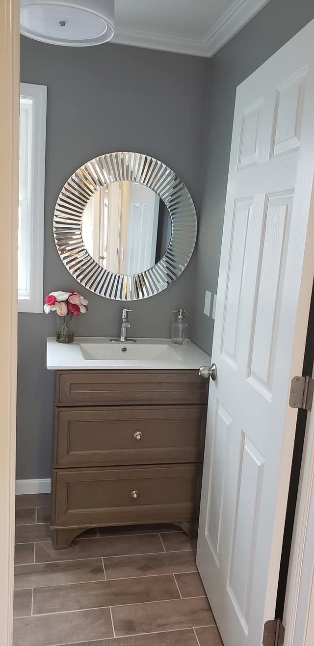 Bathroom walls painted light gray, with white trim, door, crown molding, and baseboards.