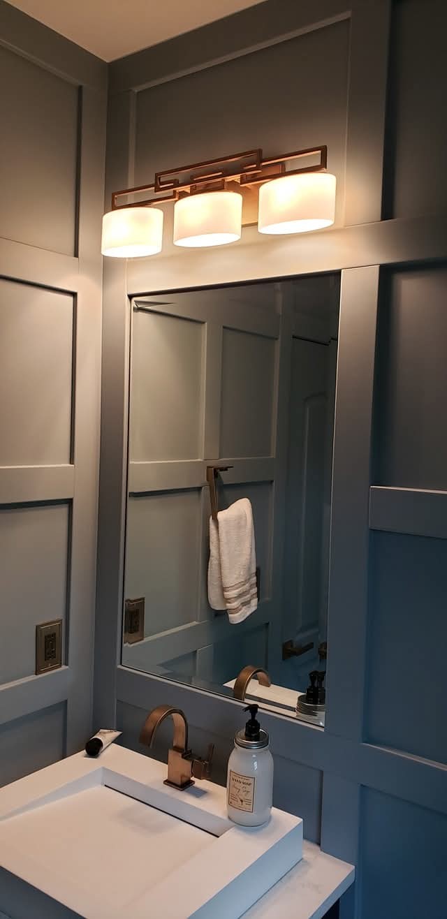 Bathroom walls with wainscoting and trim painted a light blue-gray finish.