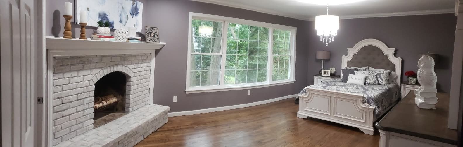 Bedroom with painted gray walls, white trim, and whitewashed brick fireplace.