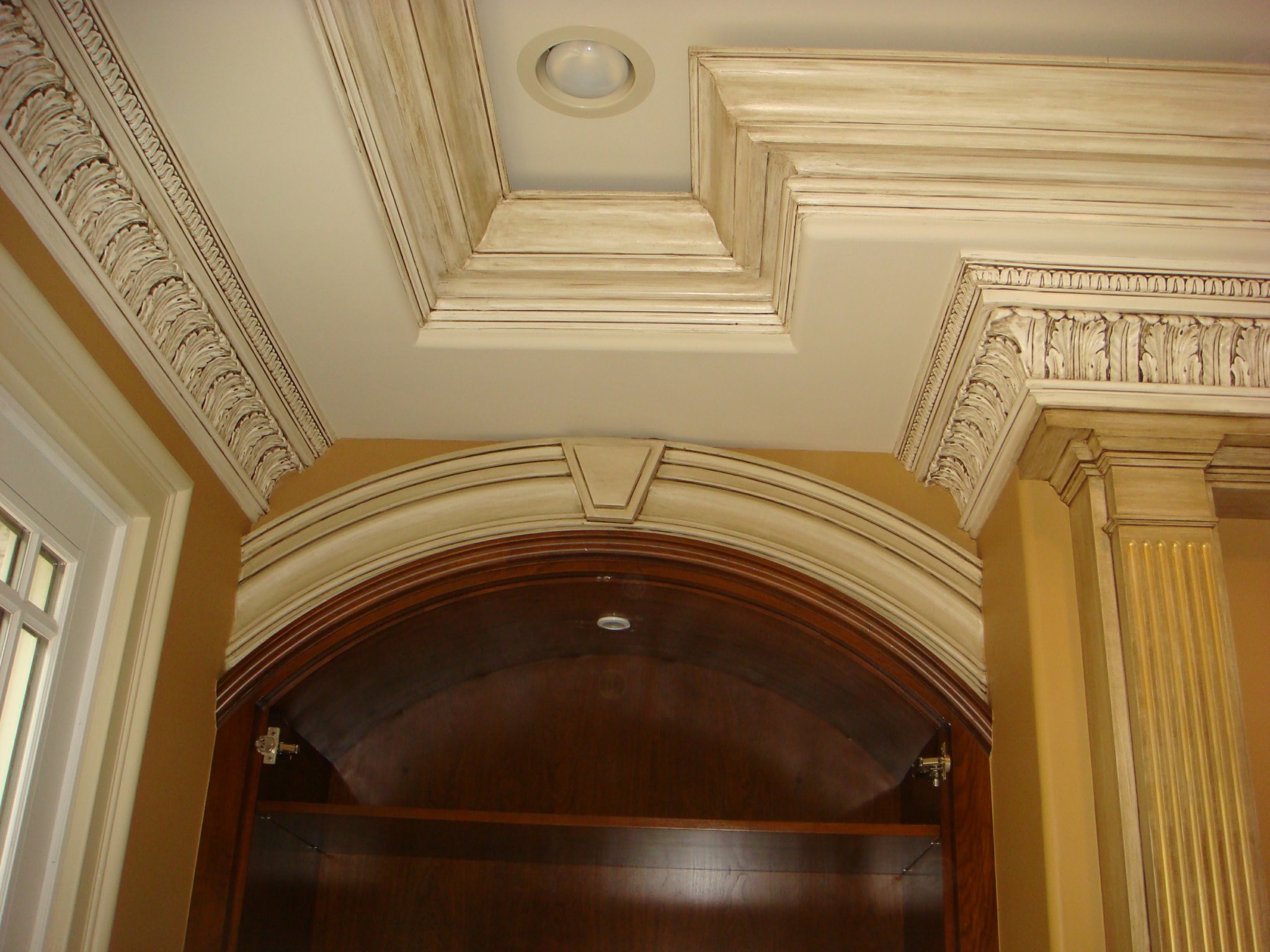 Ceiling, walls, and elaborate crown moldings with antiqued finish and recessed lighting.