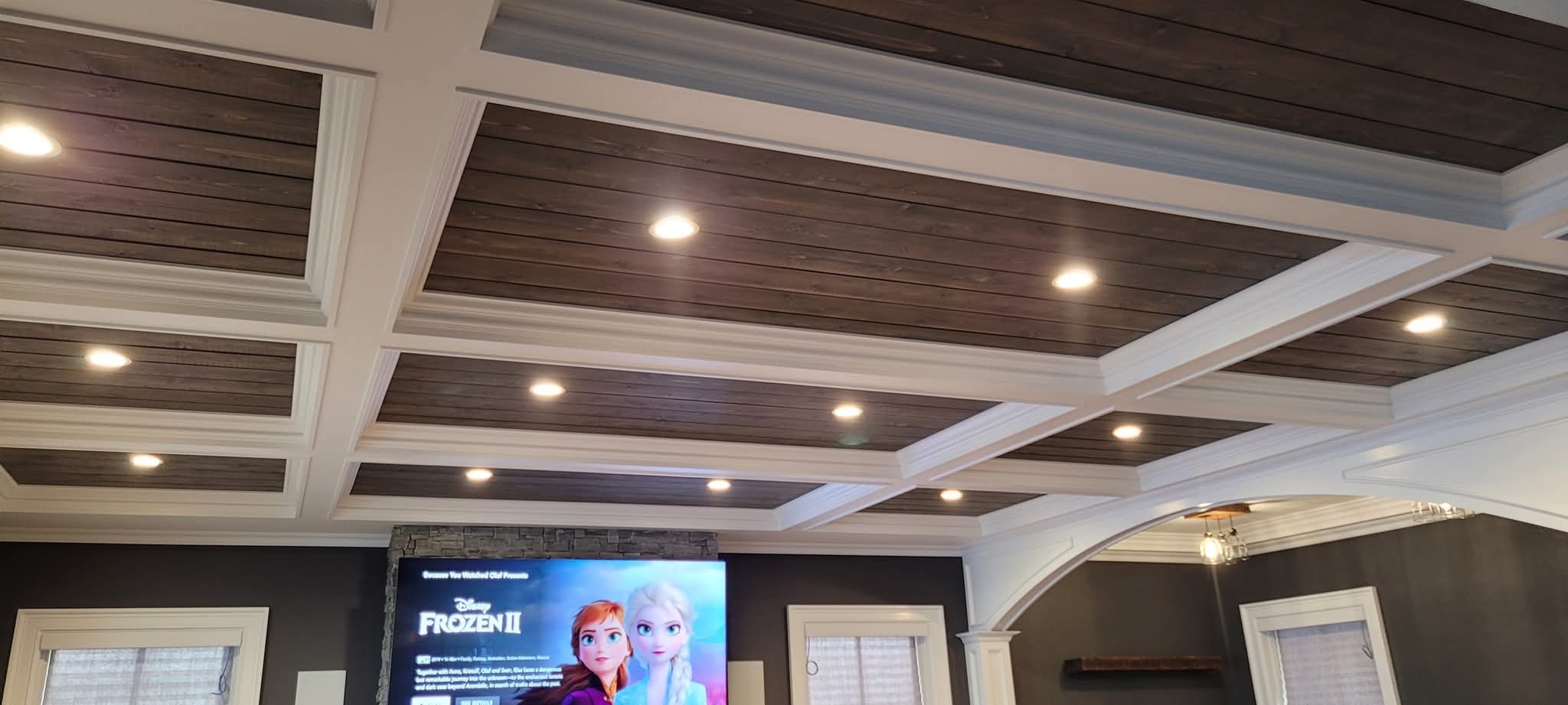 Coffered ceiling with white trim and stained wood planks, after painting.