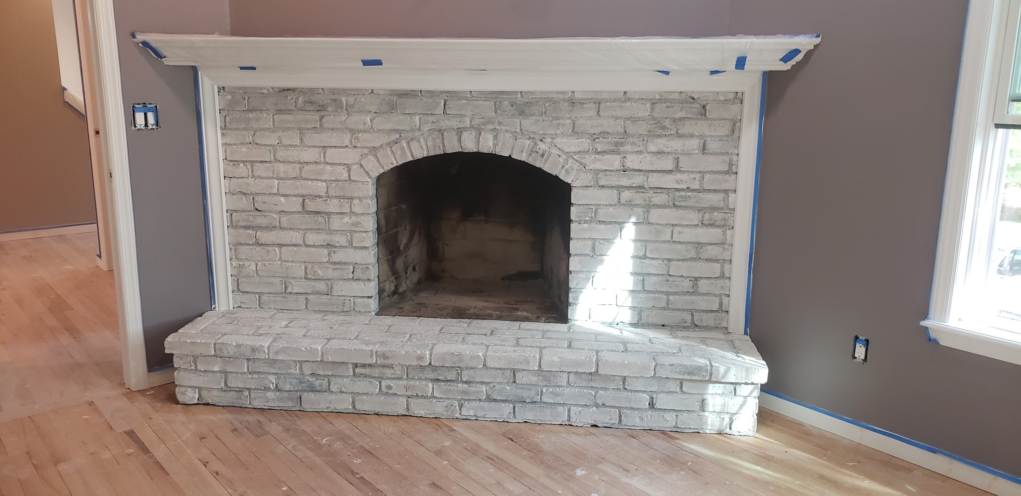 Fireplace brick with light gray painted finish and white mantel; walls prepped.