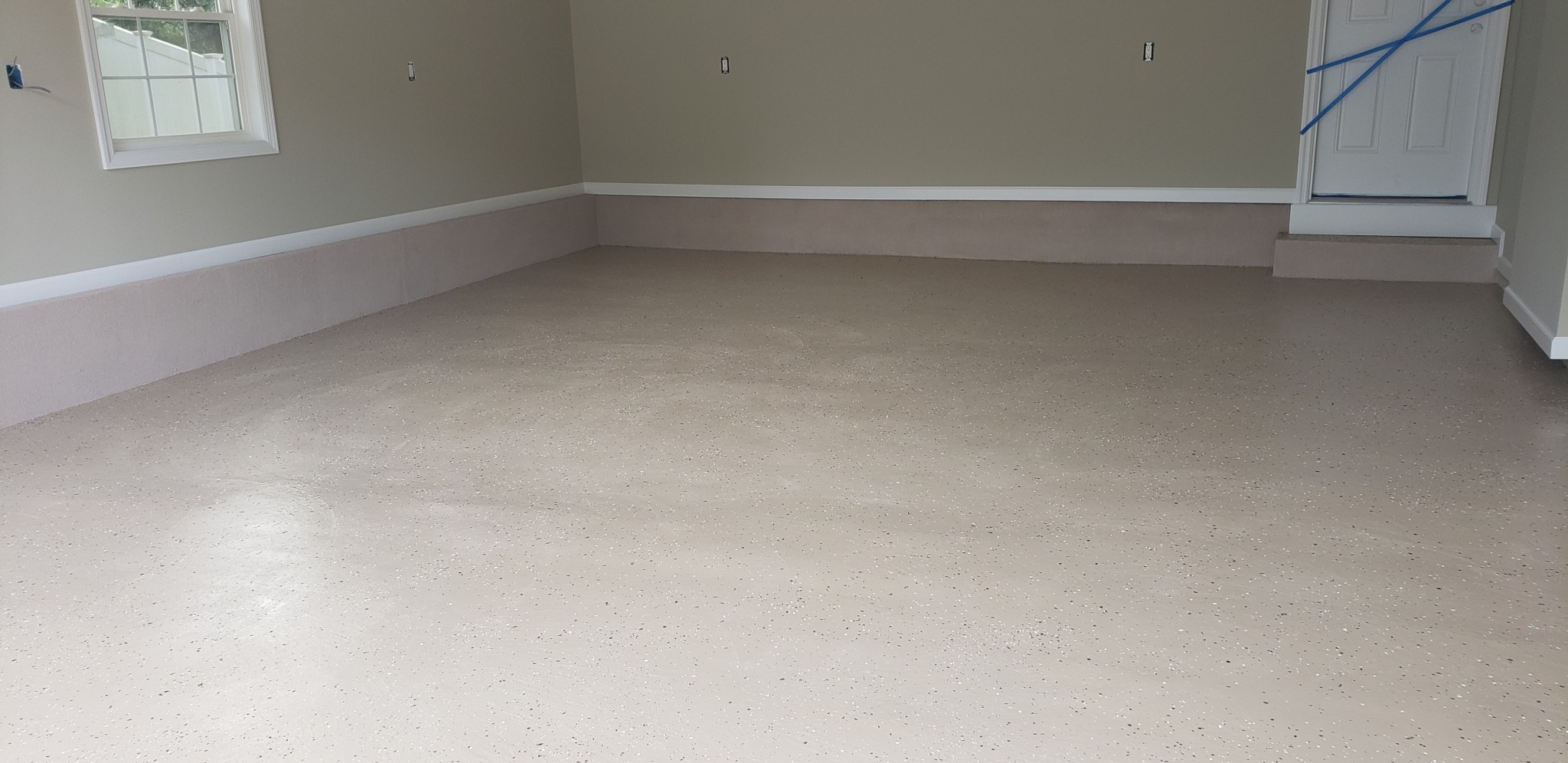 Garage interior with newly coated concrete floor and freshly painted walls.