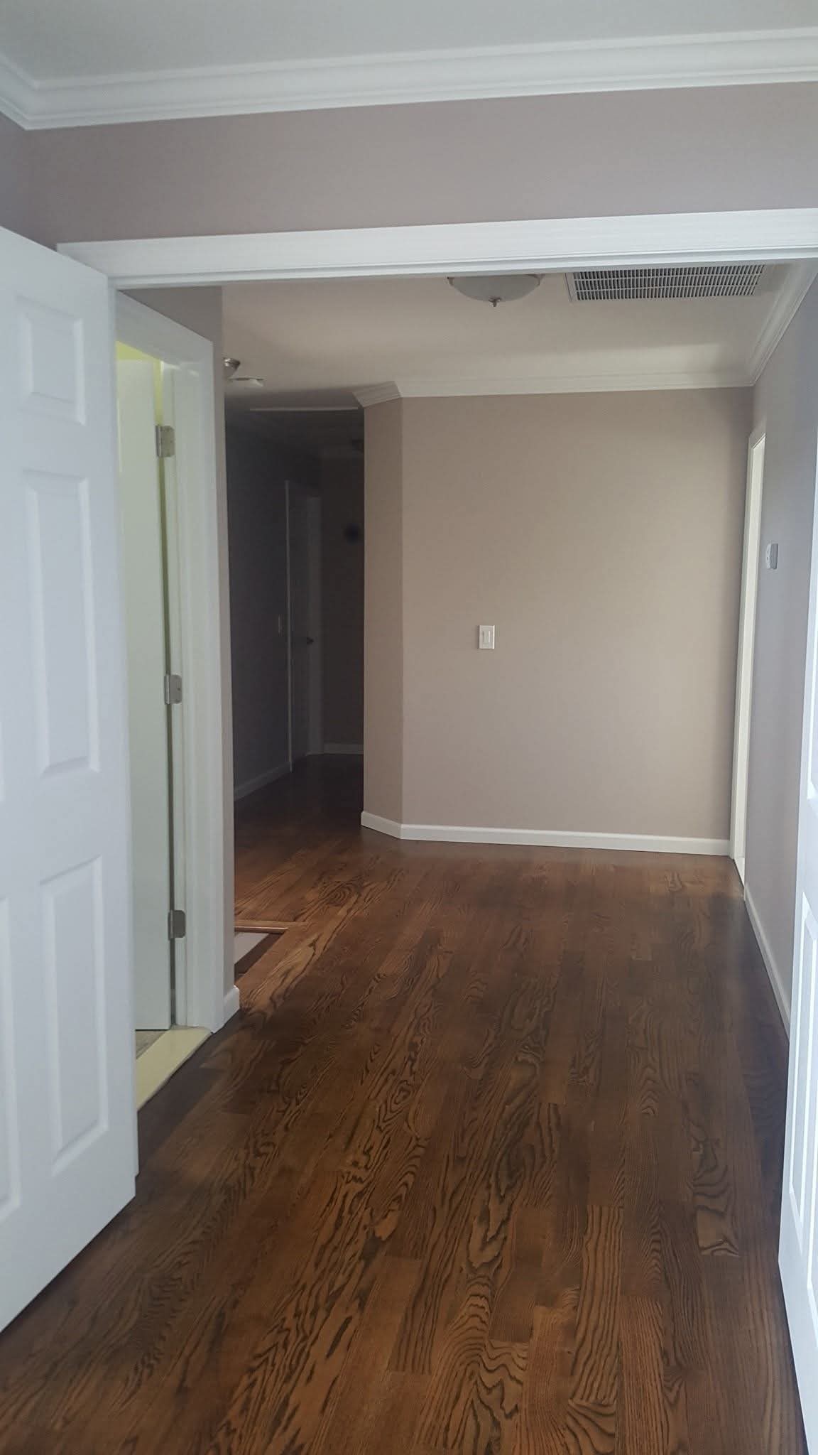 Interior room with freshly painted light gray walls and white trim, crown molding.