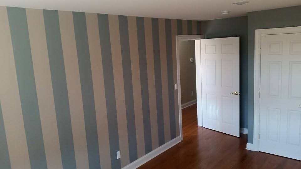 Interior room with white baseboards, striped walls, and white painted doors.