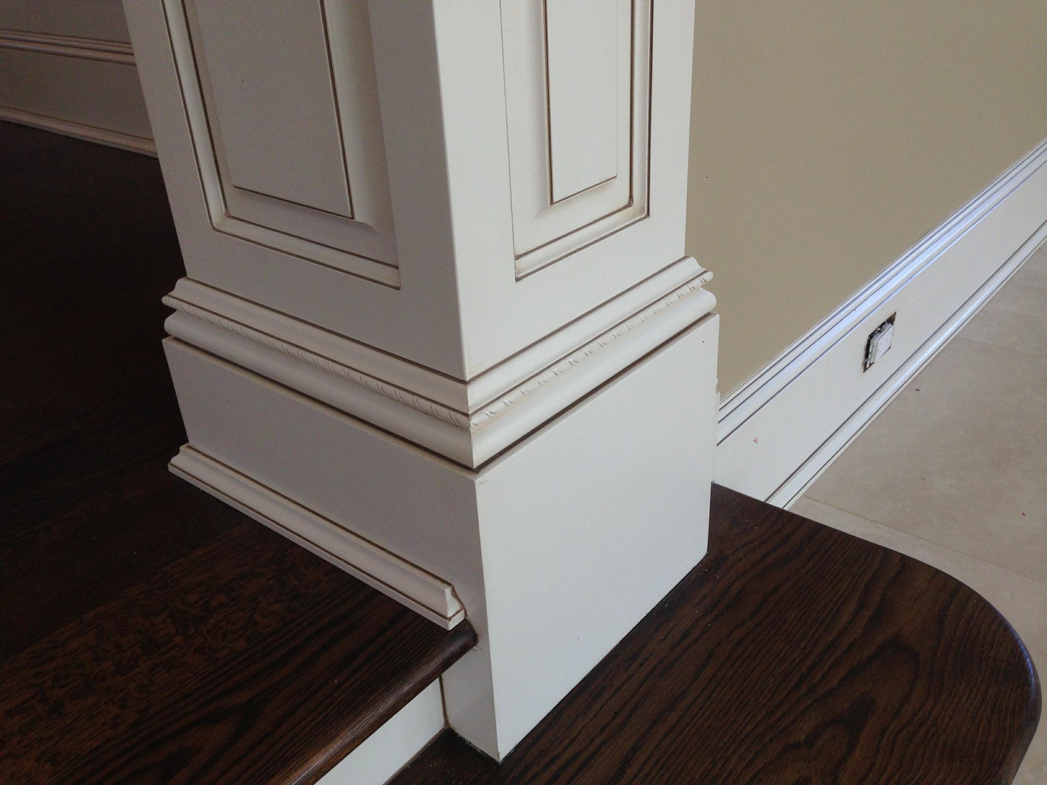 Off-white newel post and wainscoting with antiquing glaze and painted walls.