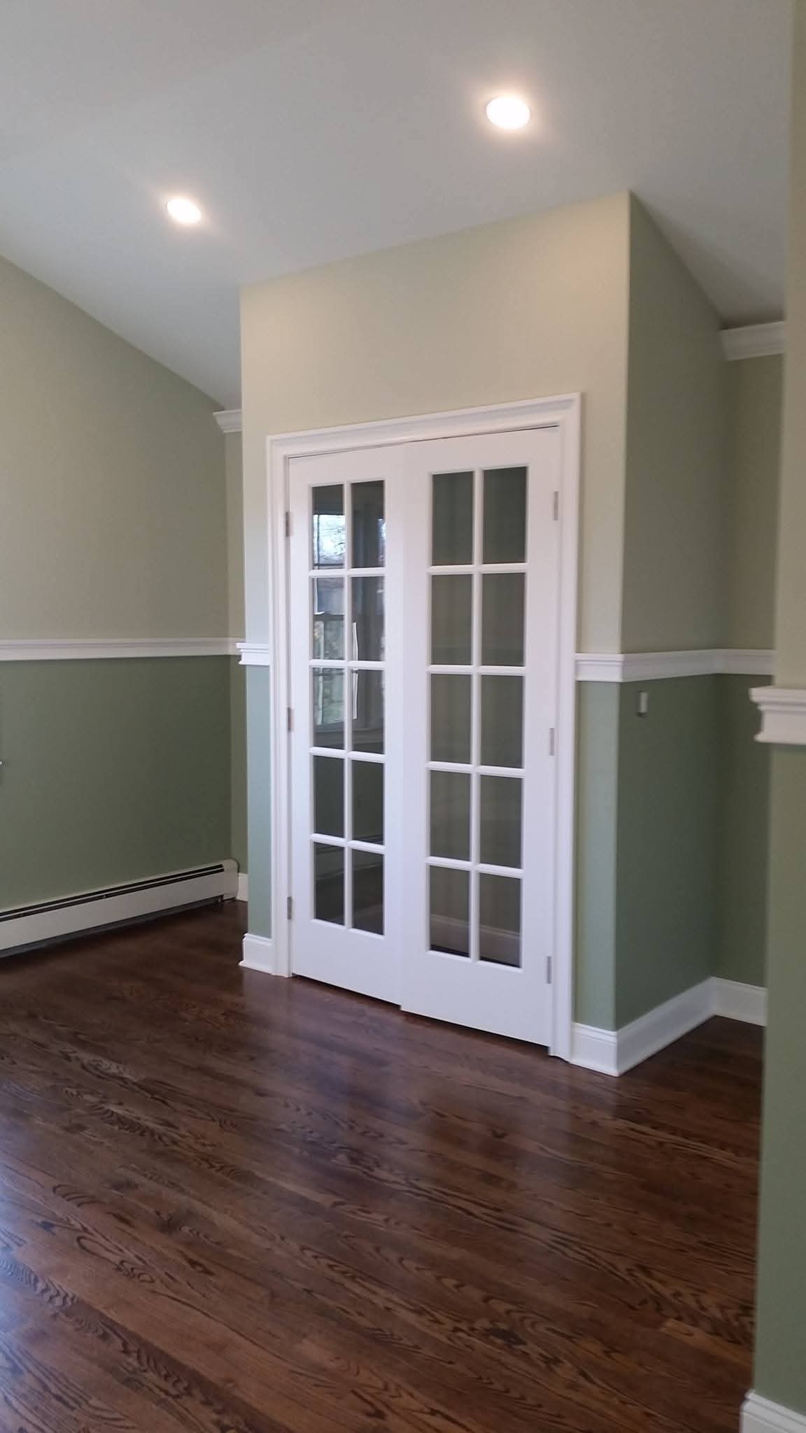 Repainted interior walls with wainscoting and white painted French doors.