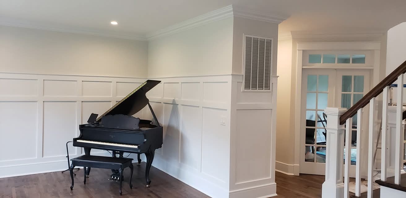 Wainscoting and crown molding painted white, with light gray walls and stained handrail.