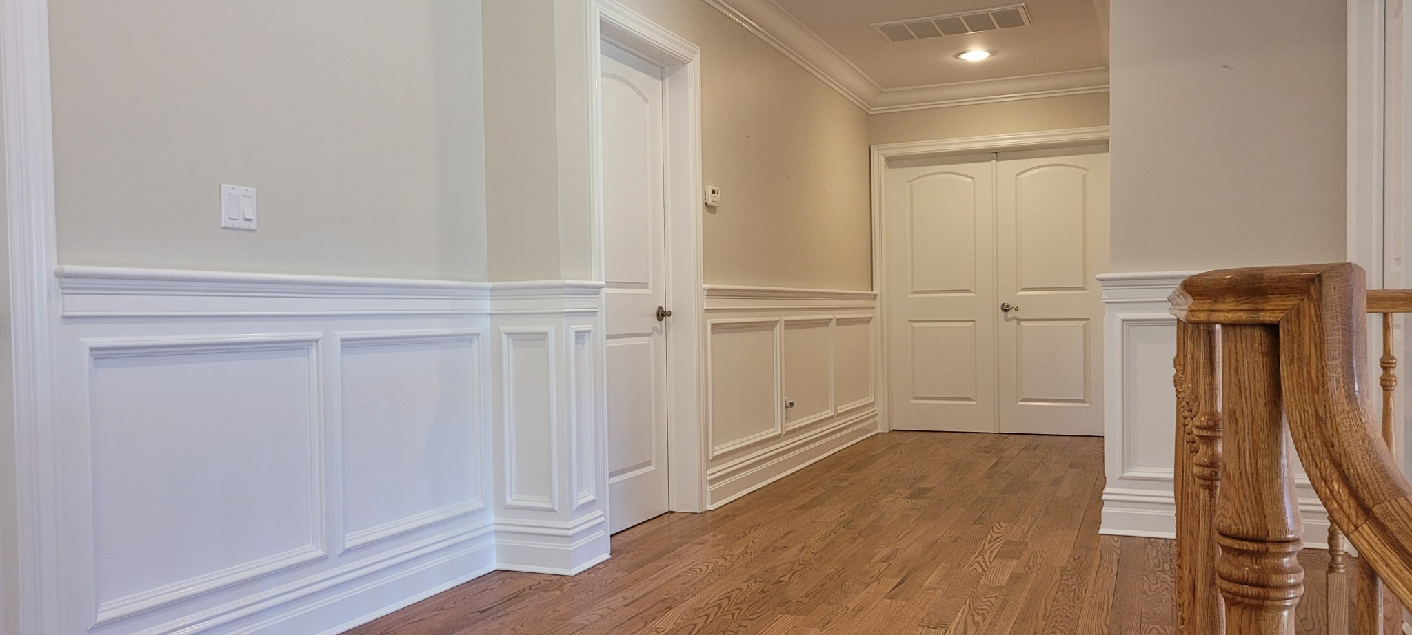 Wainscoting and trim painted white with light gray walls in a hallway.