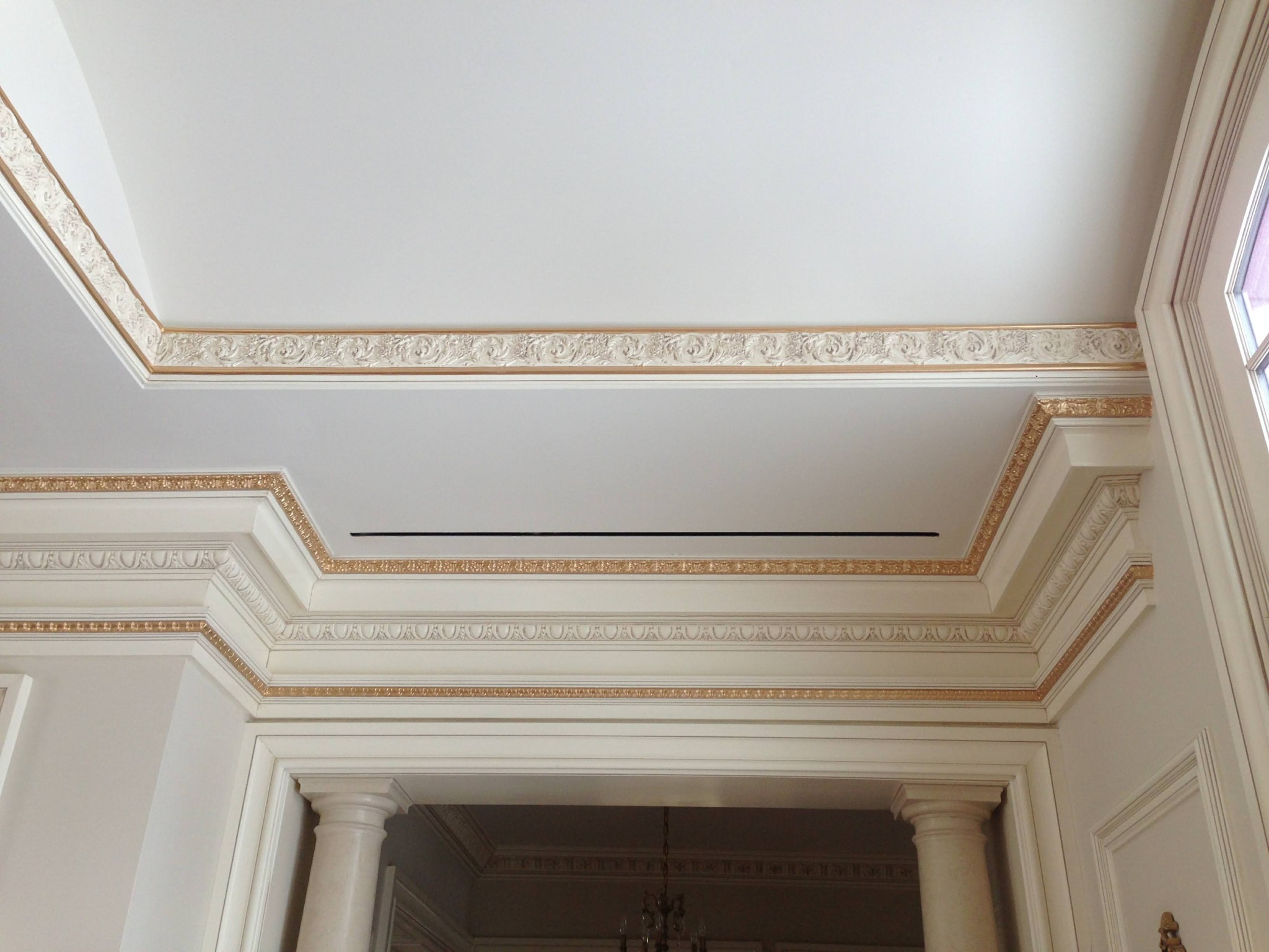 White ceiling and off-white multi-layered crown molding with gold accent painting.