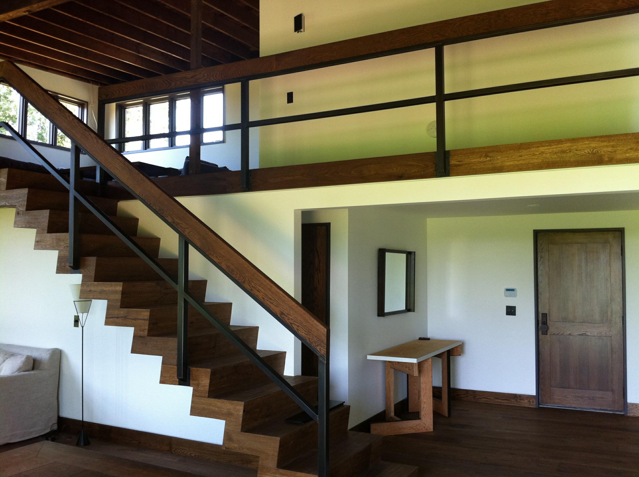 White interior walls and ceiling with stained wood staircase and railings
