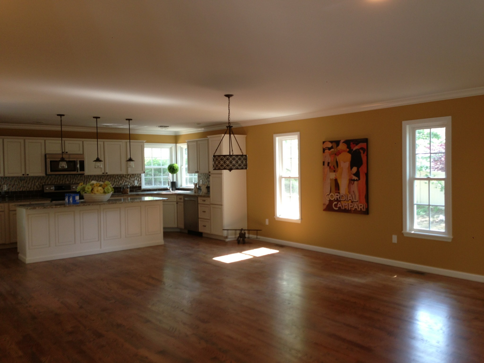 White kitchen cabinets, off-white ceilings, and light yellow walls in a kitchen and living space.