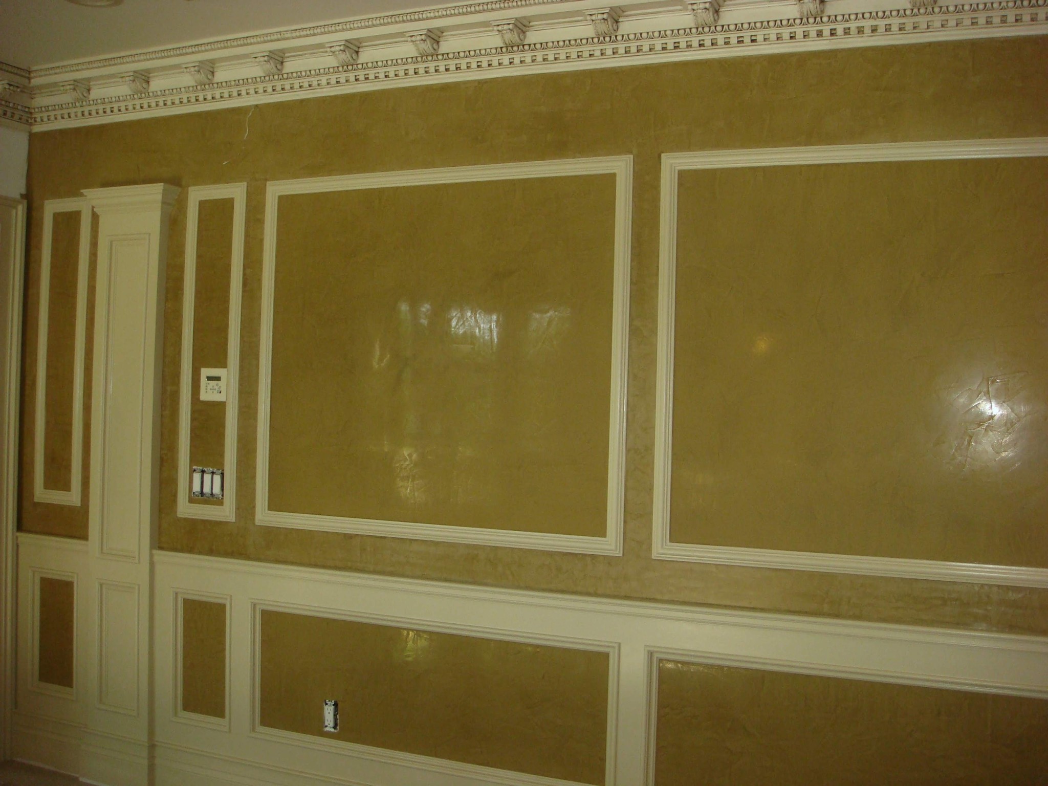 Faux finished wall panels and white painted crown molding, wainscoting, and trim.