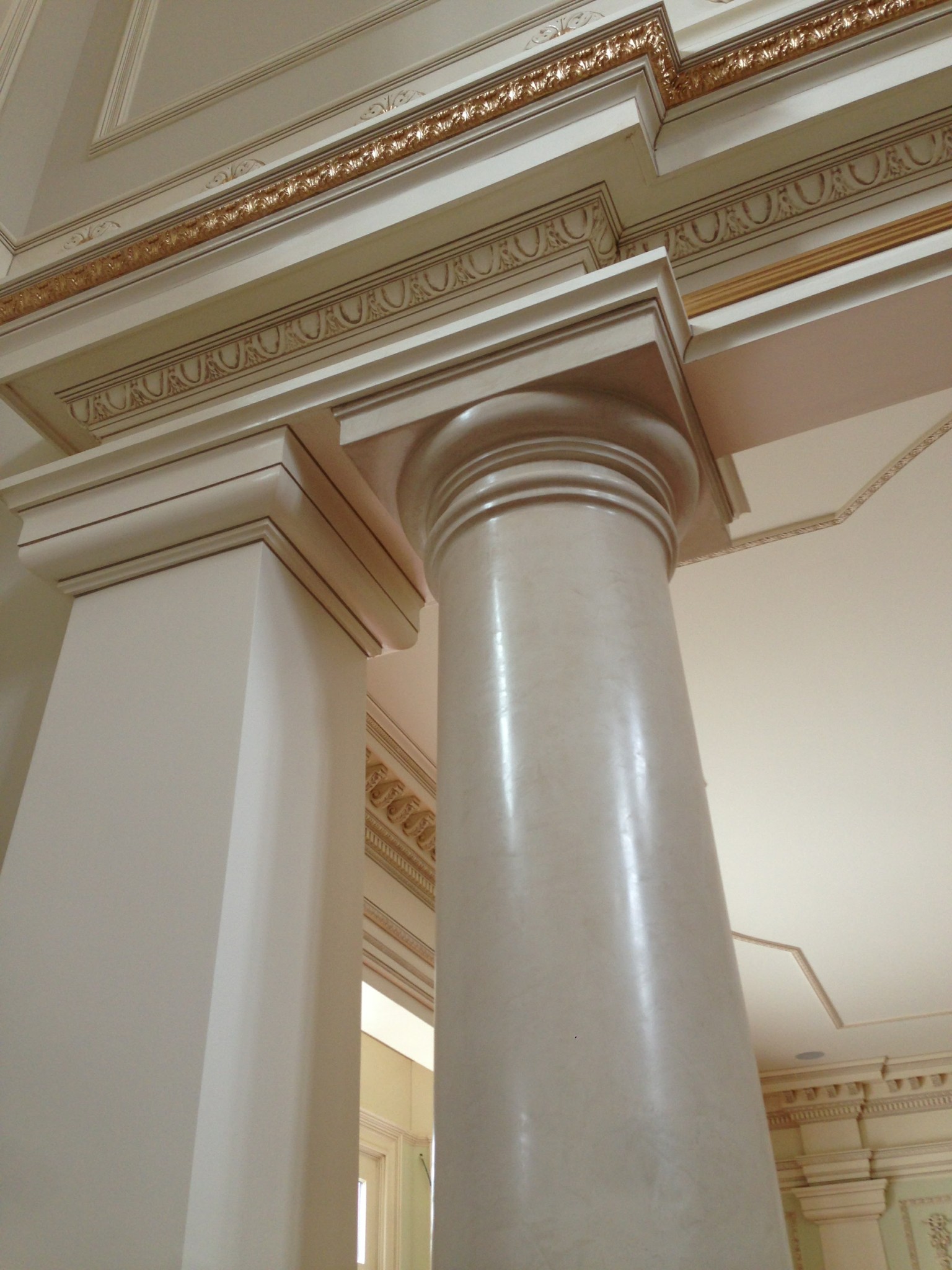 Faux marble column and painted decorative moldings with gold accents.