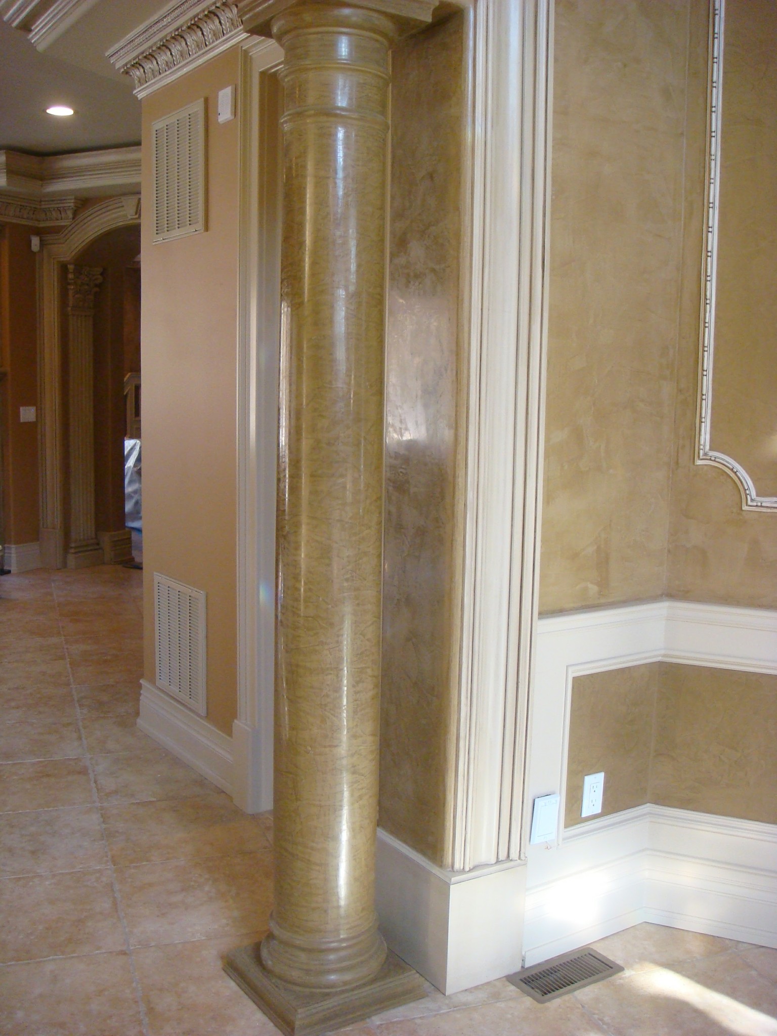 Faux marble column and textured walls with painted white trim and crown molding.
