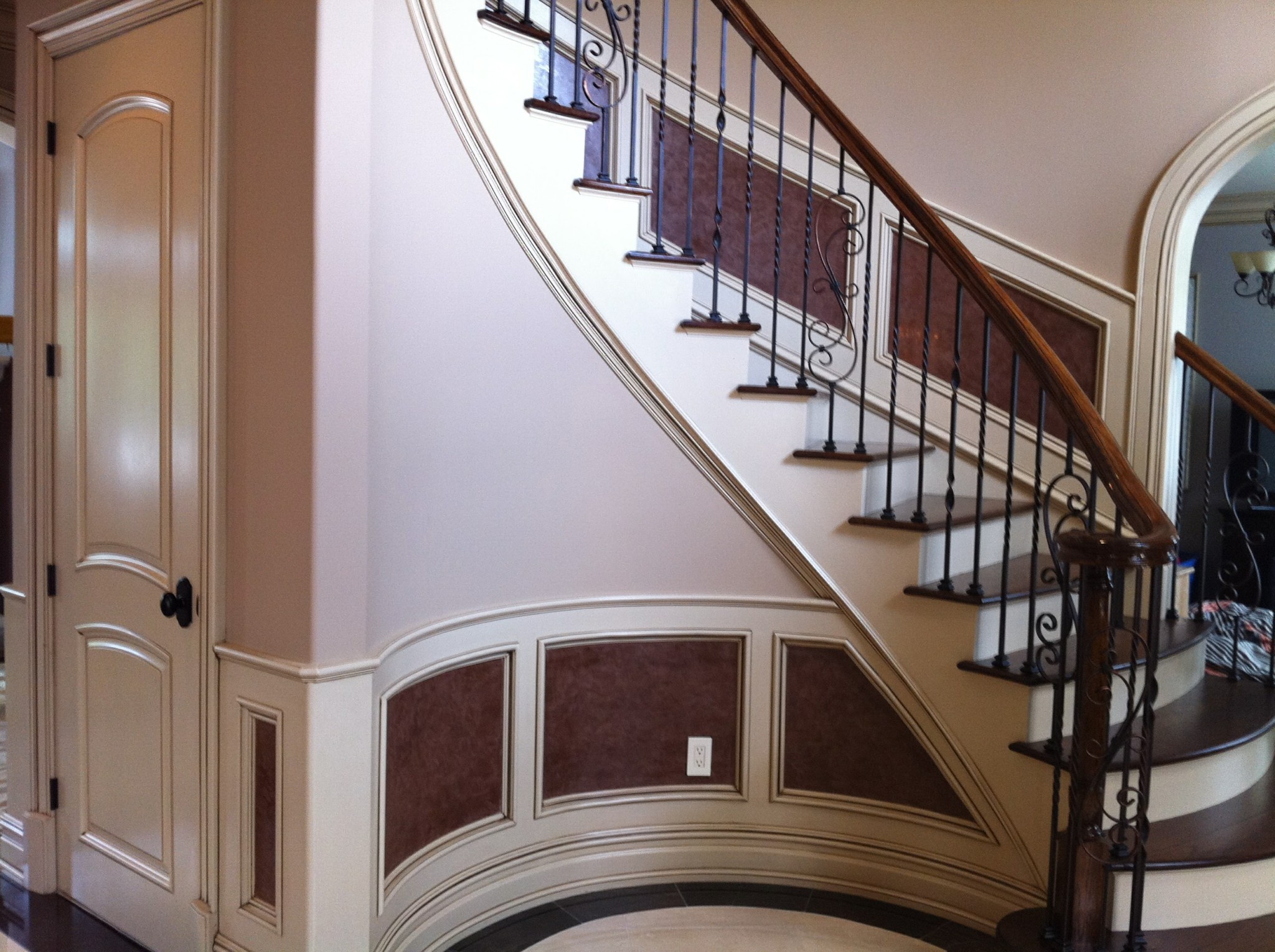 Painted wainscoting and door with faux finish panels and staircase elements.