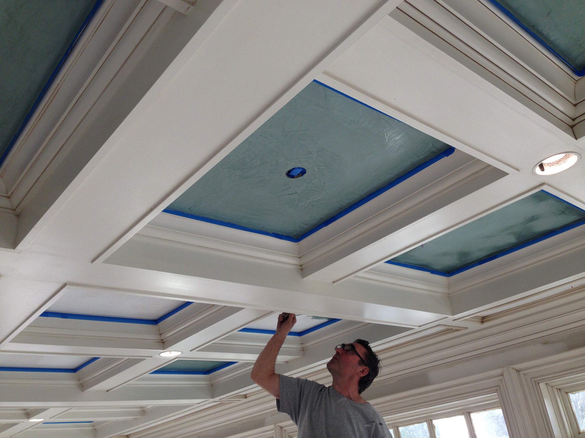 Professional painting contractor preparing a coffered ceiling with light blue recessed panels.