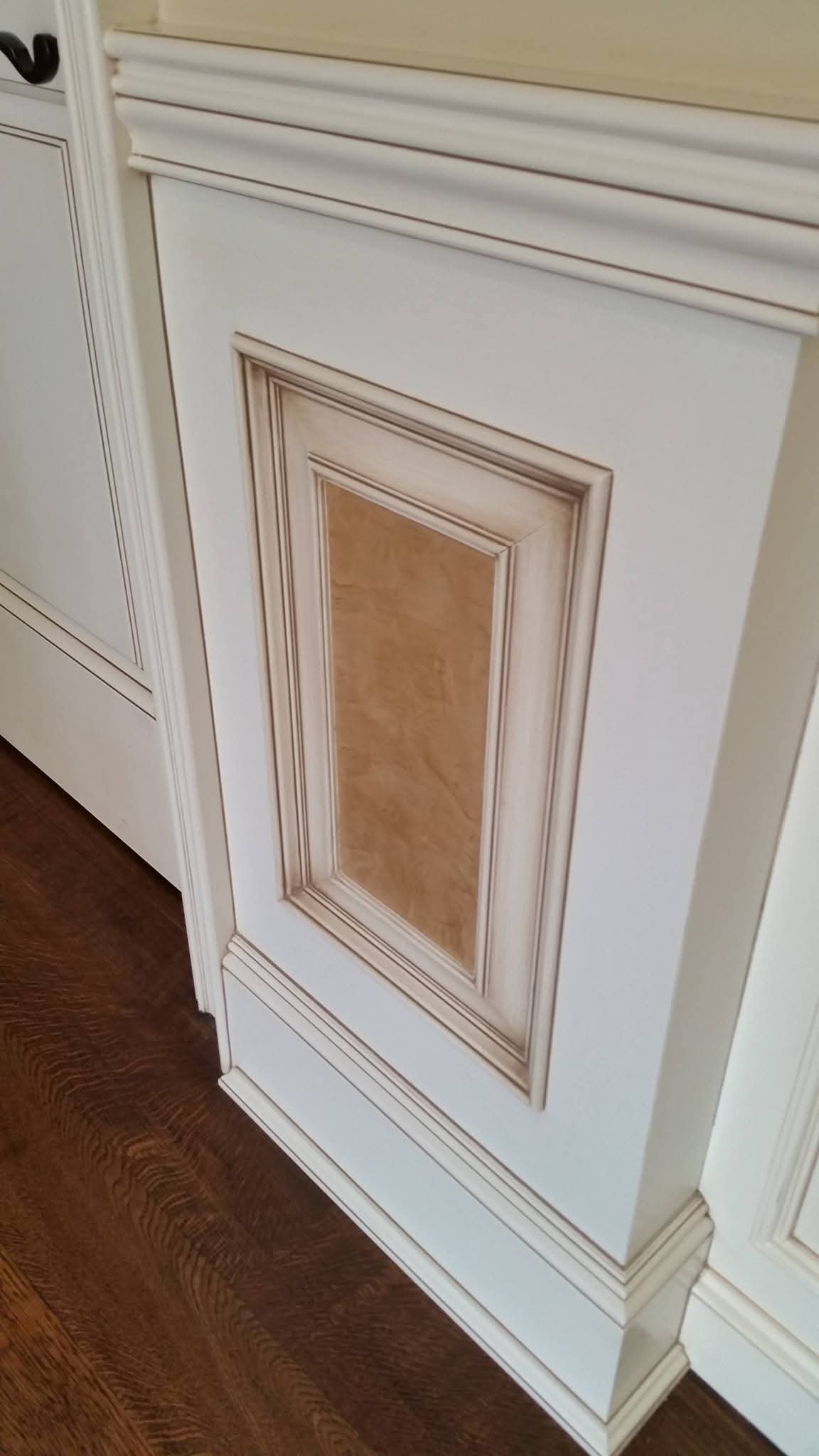 White wainscoting and trim with antiqued panel detail and wood inlay.
